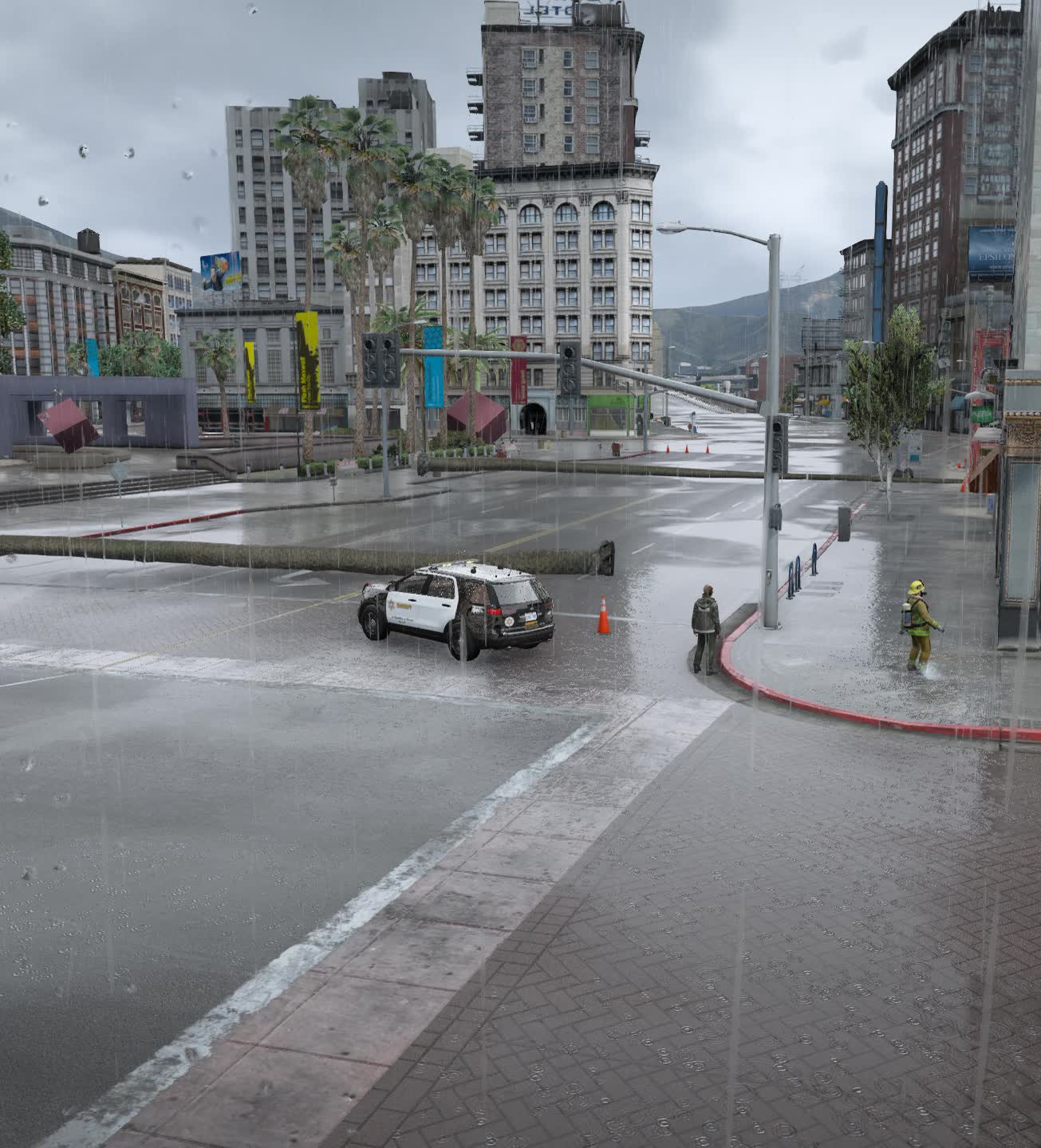 A flooded downtown junction with a police unit and a firefighter working in heavy rain