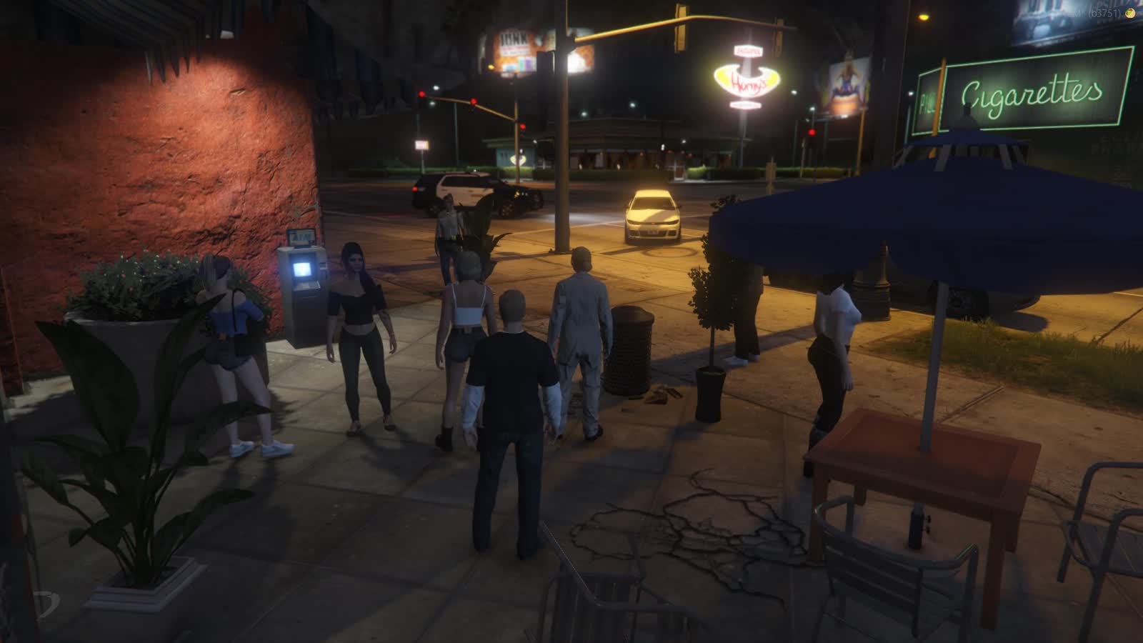 A crowd of characters on a lit pavement at night beside an ATM and a police cruiser